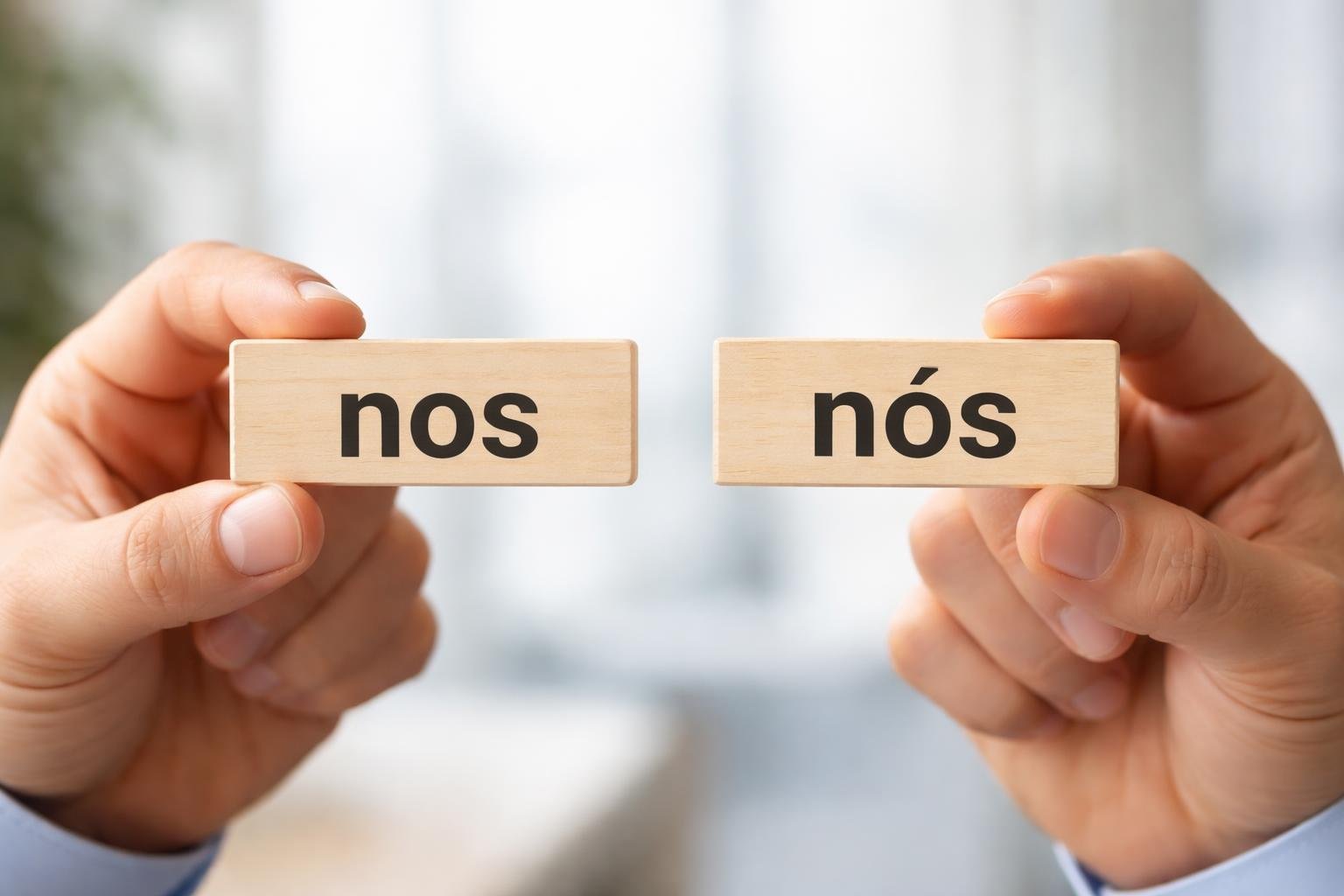 Duas mãos segurando placas de madeira com as palavras 'nos' e 'nós', em um ambiente de escritório desfocado ao fundo.